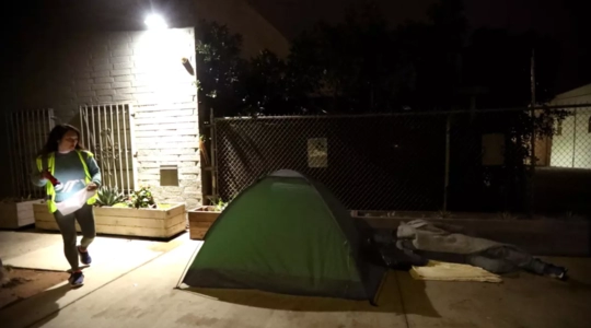 Woman in a  reflective vest counting a tent for the annual point in time count