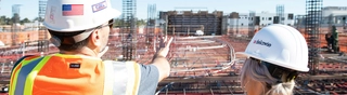 Two people looking out over a construction site foundation